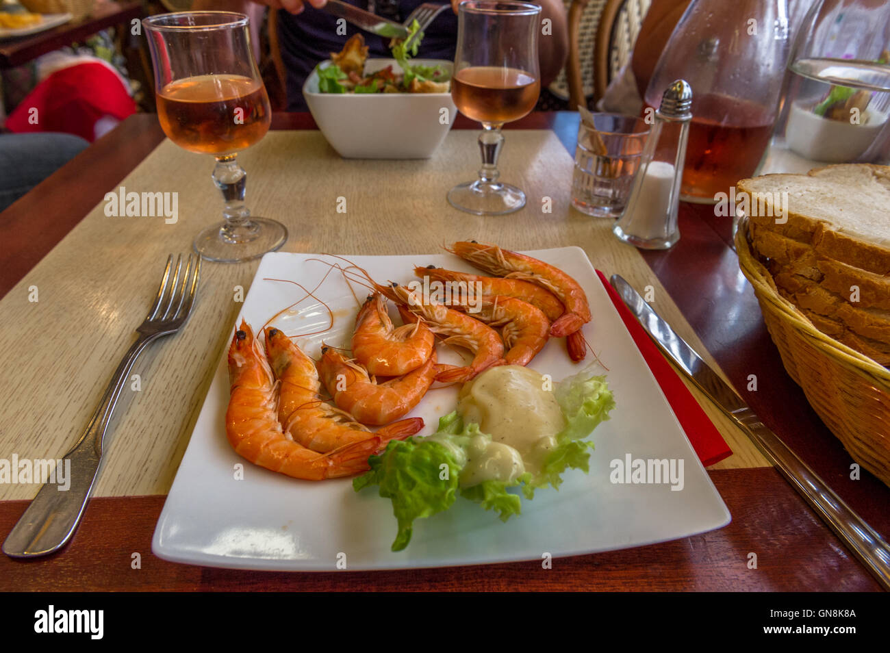 Fresh cooked king prawns and a glass of house wine in a French restaurant in St. Malo, Brittany, France Stock Photo