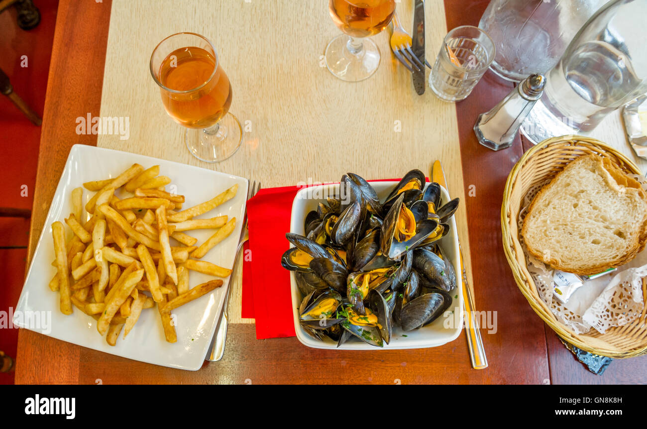 Fresh mussels, chips and a glass of house wine in a French restaurant in St. Malo, Brittany, France Stock Photo