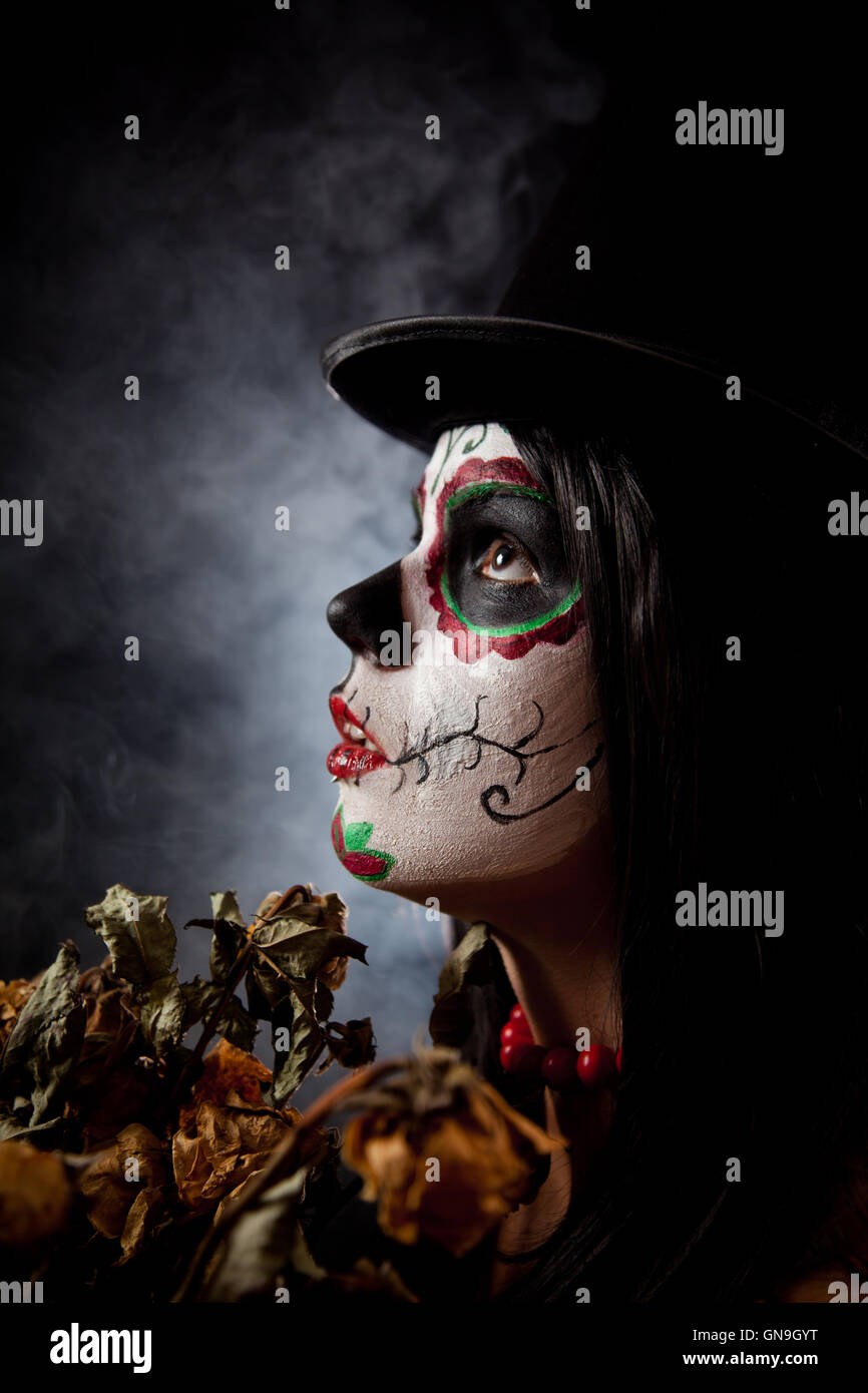 Sugar skull woman in tophat, holding dead roses Stock Photo