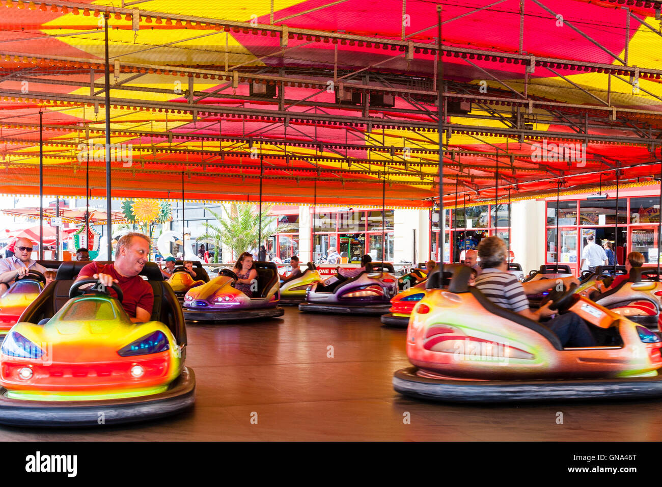 Dodgems, AKA  bumper cars, being driven around by adults and children at the seafront at Ramsgate, a Kent resort town, in the summertime. Stock Photo