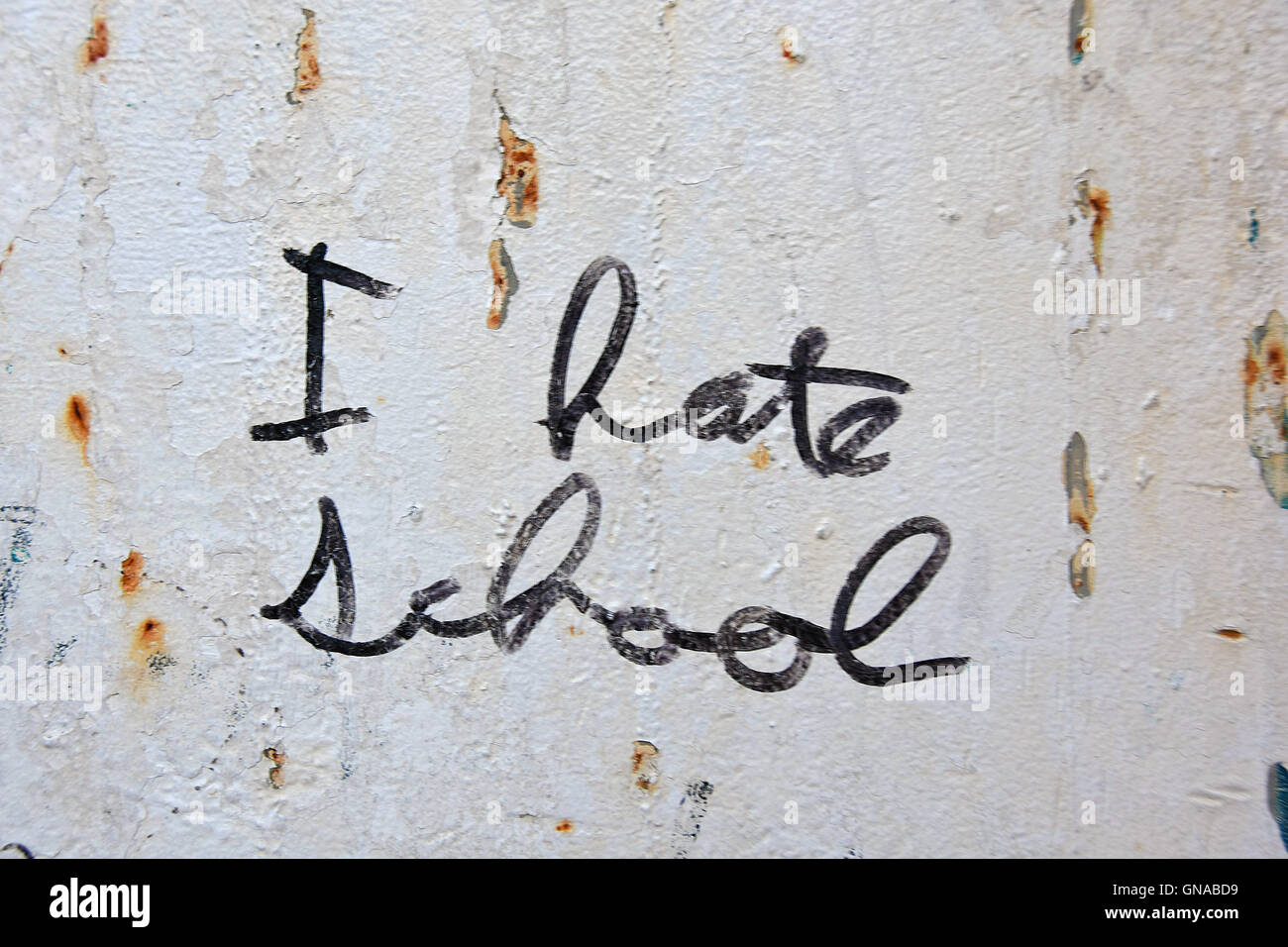 scribbled graffiti I hate school on rust speckled metal wall Stock Photo