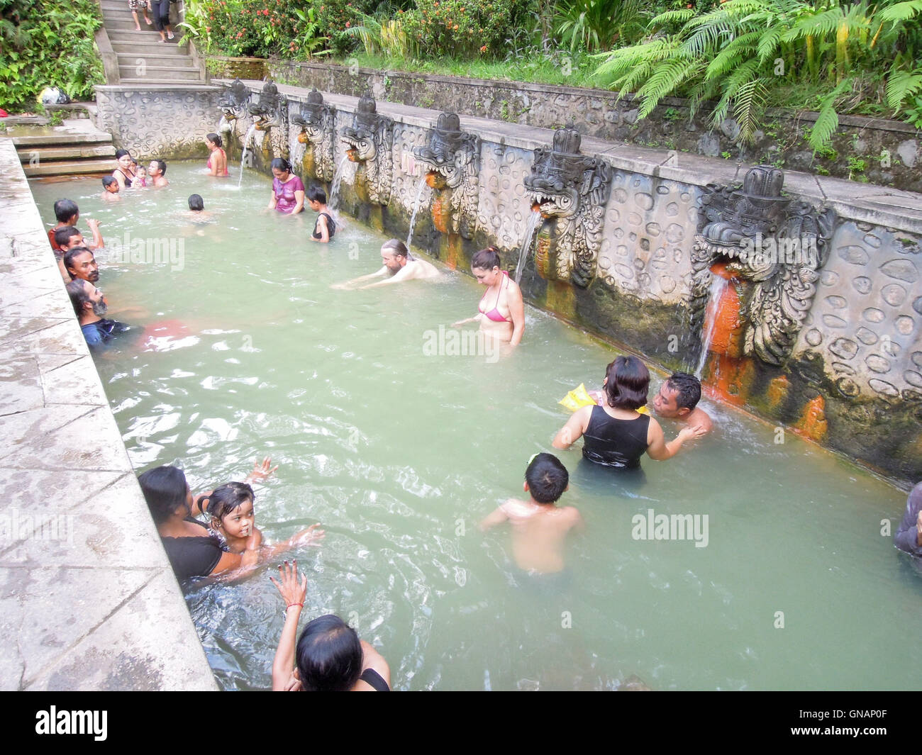 Banjar (Bali), Indonesia - 8 february 2013: People under the water jets of the public pool at Banjar on the island of Bali, Indo Stock Photo