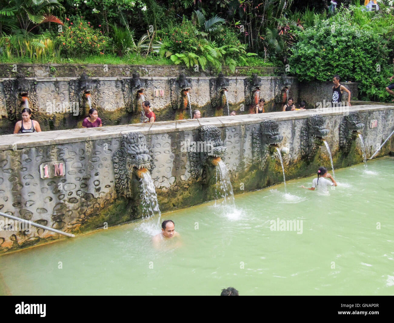 Banjar (Bali), Indonesia - 8 february 2013: People under the water jets of the public pool at Banjar on the island of Bali, Indo Stock Photo