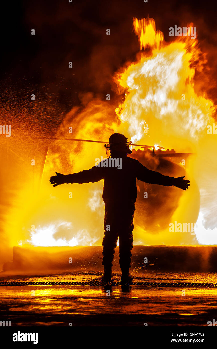 Firechief with arms open in front of fire Stock Photo