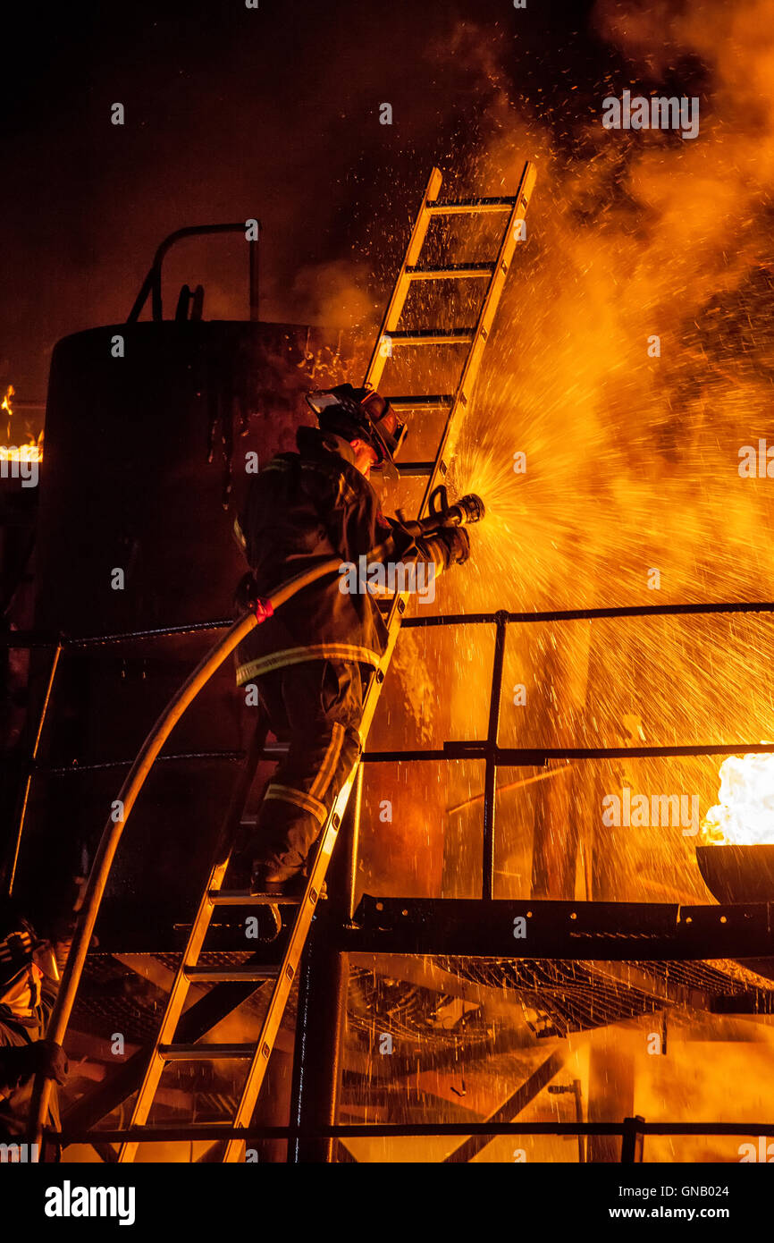 Firefighter fighting fire on a ladder Stock Photo