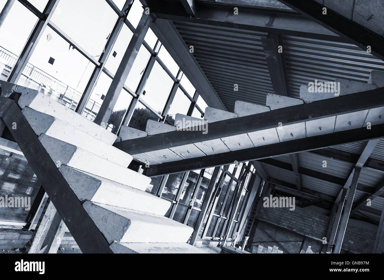 Generic industrial building is under construction. Interior fragment with unfinished concrete stairway, blue toned photo with se Stock Photo