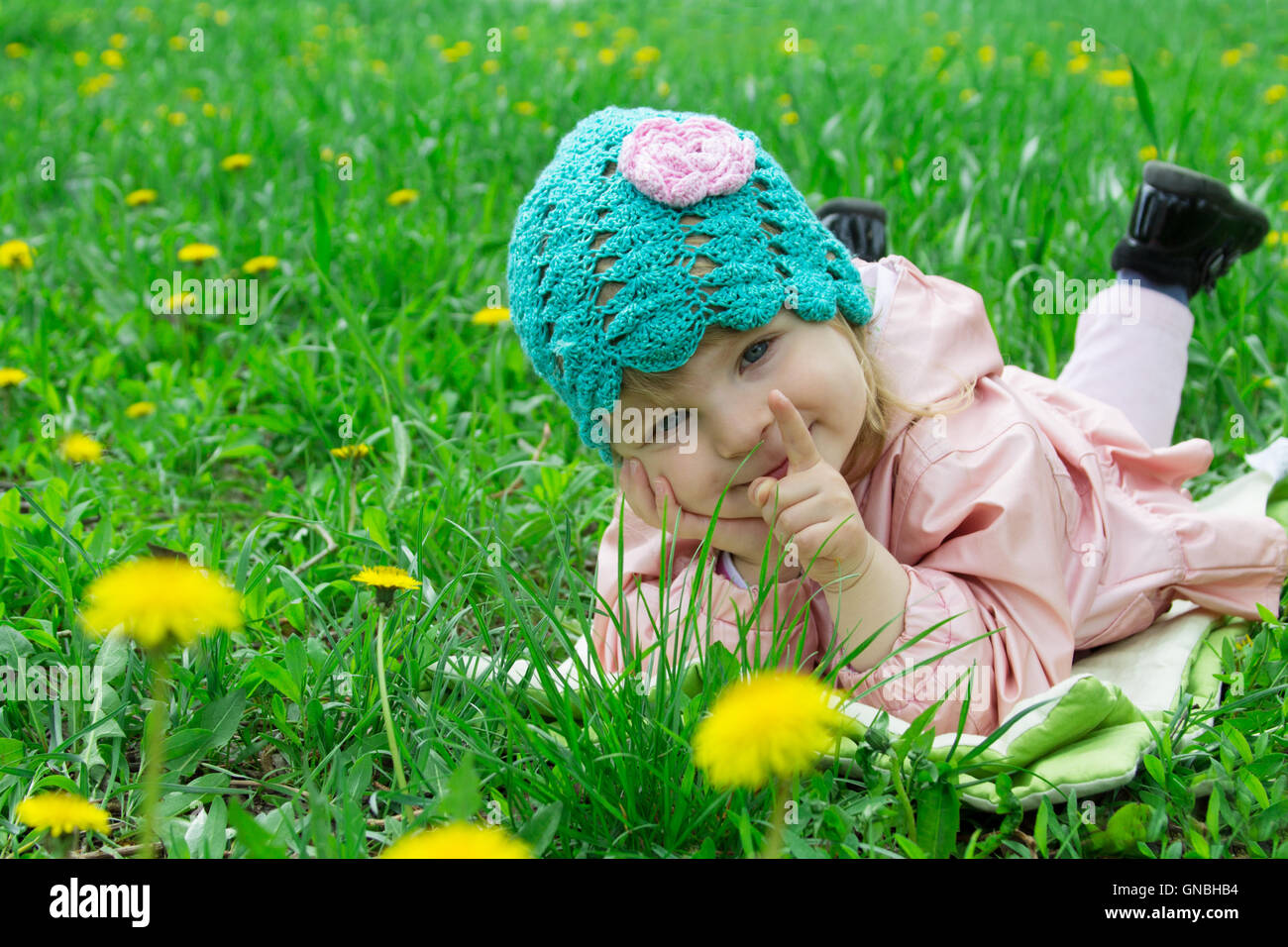 Baby girl lying among field of dandelions Stock Photo - Alamy