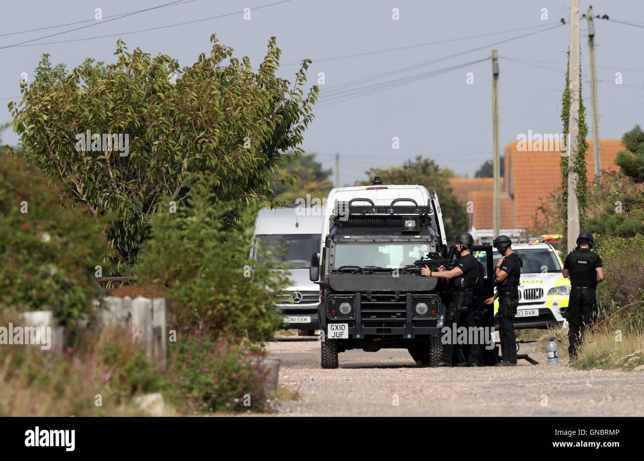 Armed police at the scene on Harbour Road, Pagham, West Sussex, where they are in a stand-off with a 72-year-old man who is thought to have a gun. Stock Photo