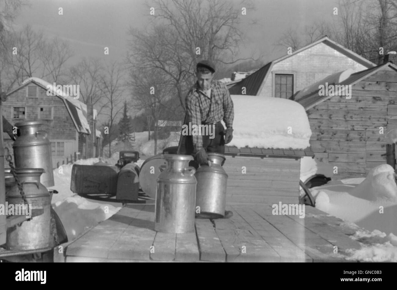 Farmer bringing milk churns to Crossroads early in morning where they are picked up by co-op farmers and delivered to city, near Woodstock, Vermont, USA, Marion Post Wolcott, U.S. Farm Security Administration, March 1940 Stock Photo