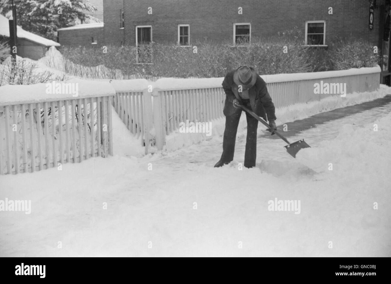 Man Clearing Snow from Sidewalk after Heavy Snowfall, Woodstock, Vermont, USA, Marion Post Wolcott for Farm Security Administration, March 1940 Stock Photo