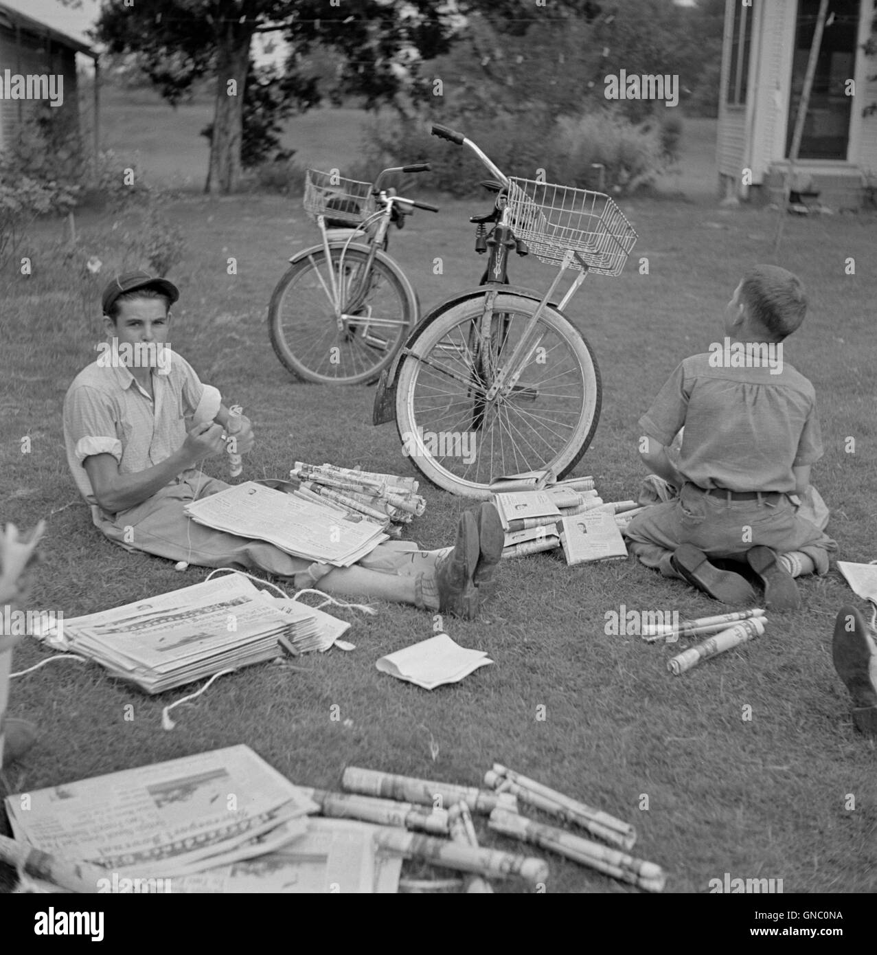 Two Boys Folding Newspapers before Starting their Afternoon Deliveries, near Natchitoches, Louisiana, USA, Marion Post Wolcott for Farm Security Administration, July 1940 Stock Photo