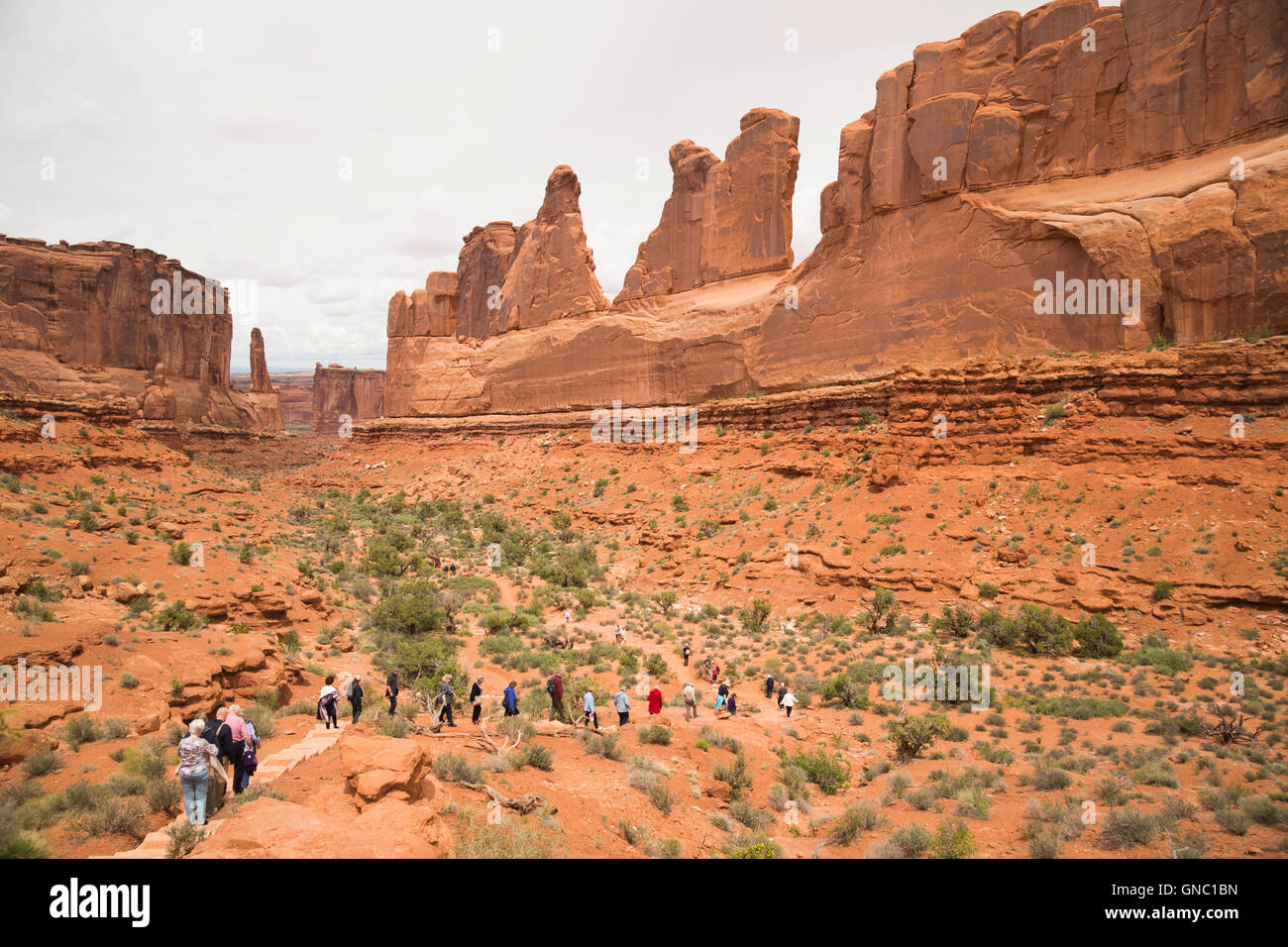 Tourists walking single file on Park Avenue Trail in Arches National Park Moab Urtah Stock Photo