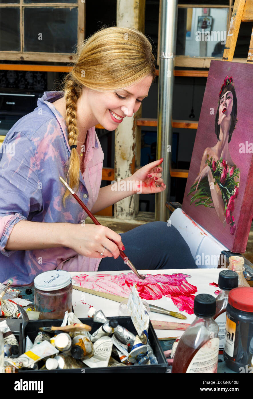 Blonde Woman  with Paint Brush and Canvas in a Painter Studio Stock Photo