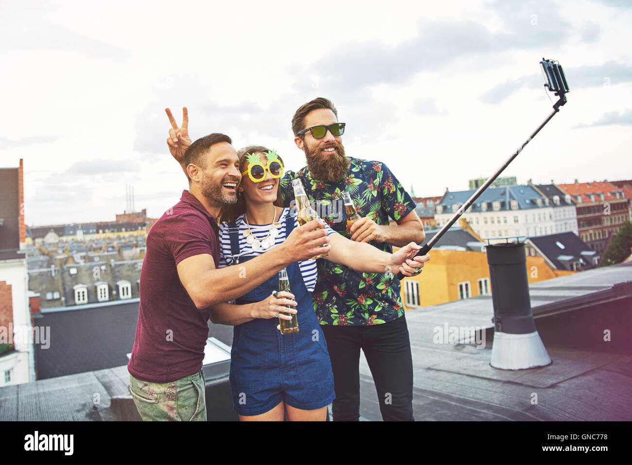 Bearded friend giving rabbit ears to man with beer while woman in ...