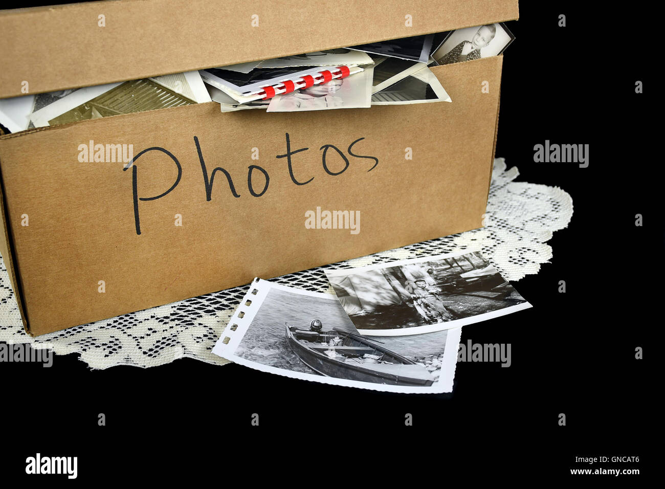 Vintage family photo collection in brown cardboard box on lace doily. Stock Photo