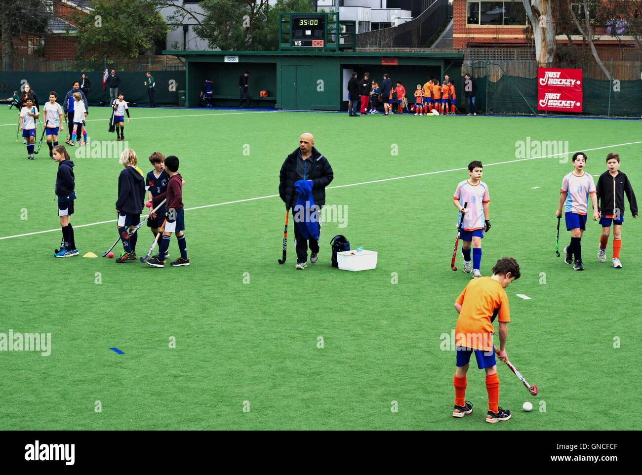 Junior field hockey players and coach warming up before a game, in