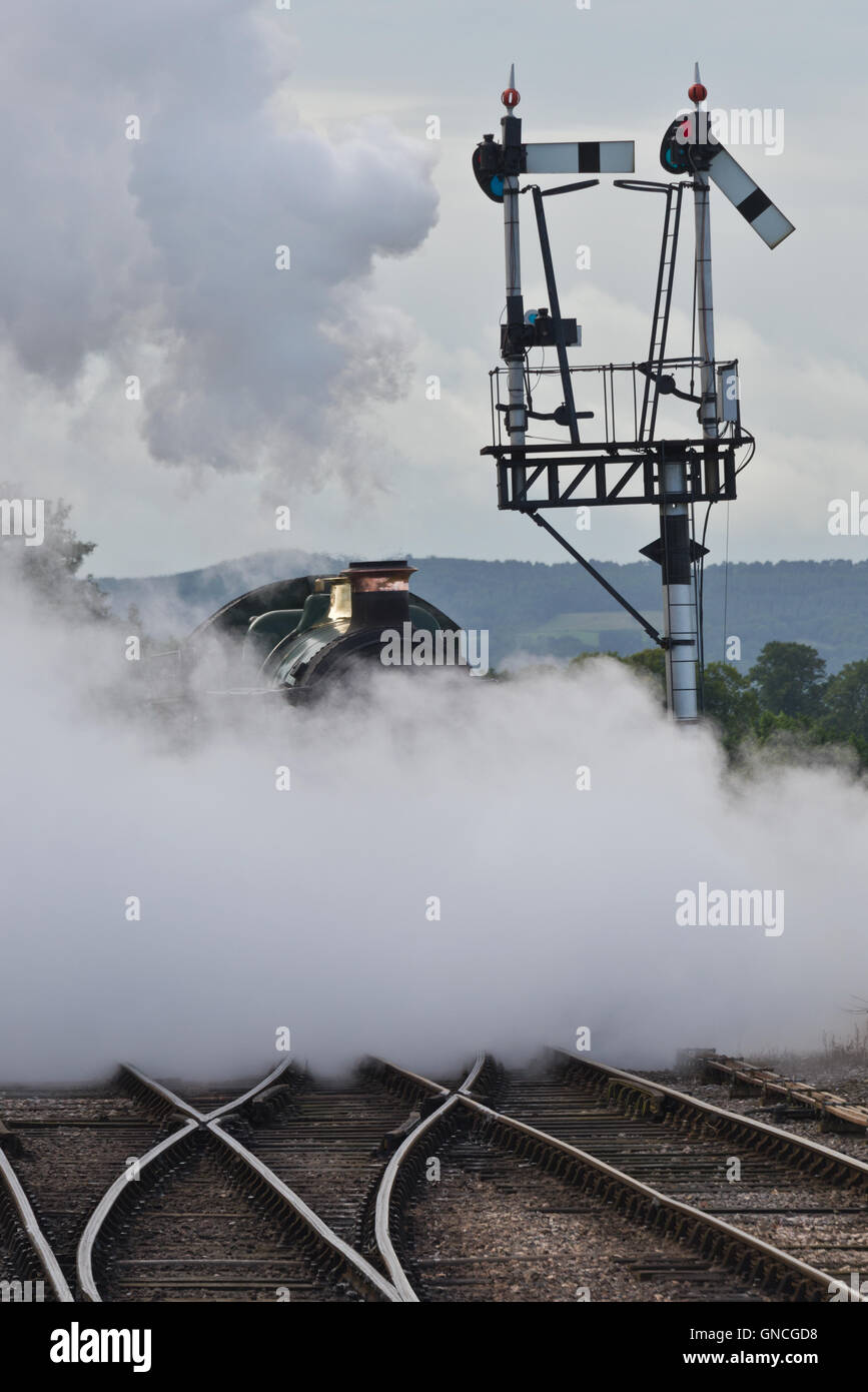 A steam engine (6960) shrouded in steam as it approaches  Bishops Lydeards station on the West Somerset railway Stock Photo