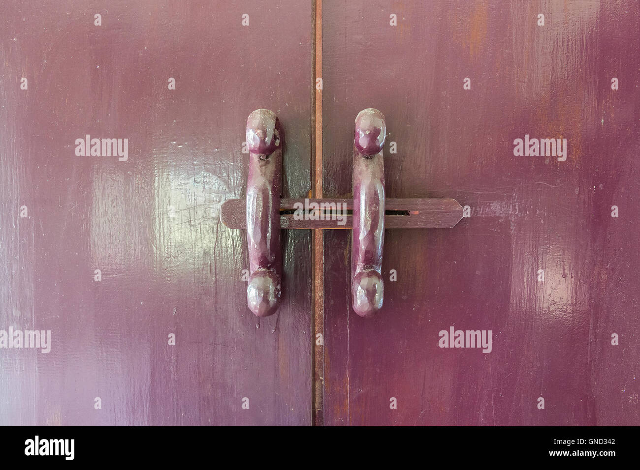 Old style wooden latch in red-purple color. Stock Photo