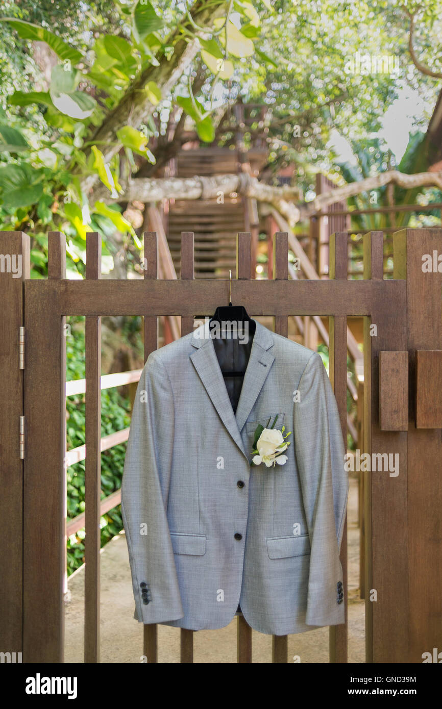 Grooms jacket hanging by fence. Stock Photo