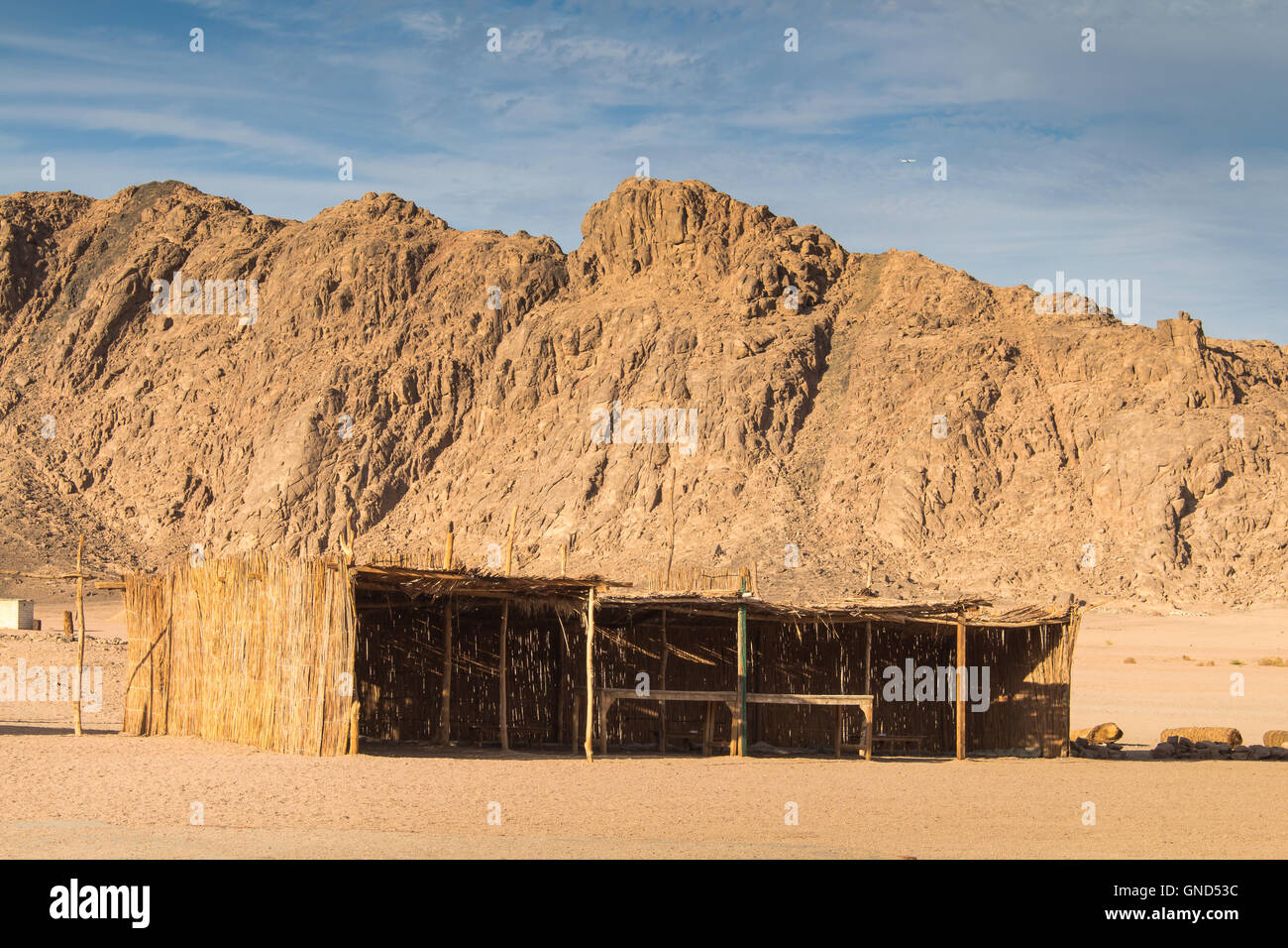 Rocky mountains in the sand color in the desert in Egypt. Bedouin building for the guests. Cloudy sky. Stock Photo