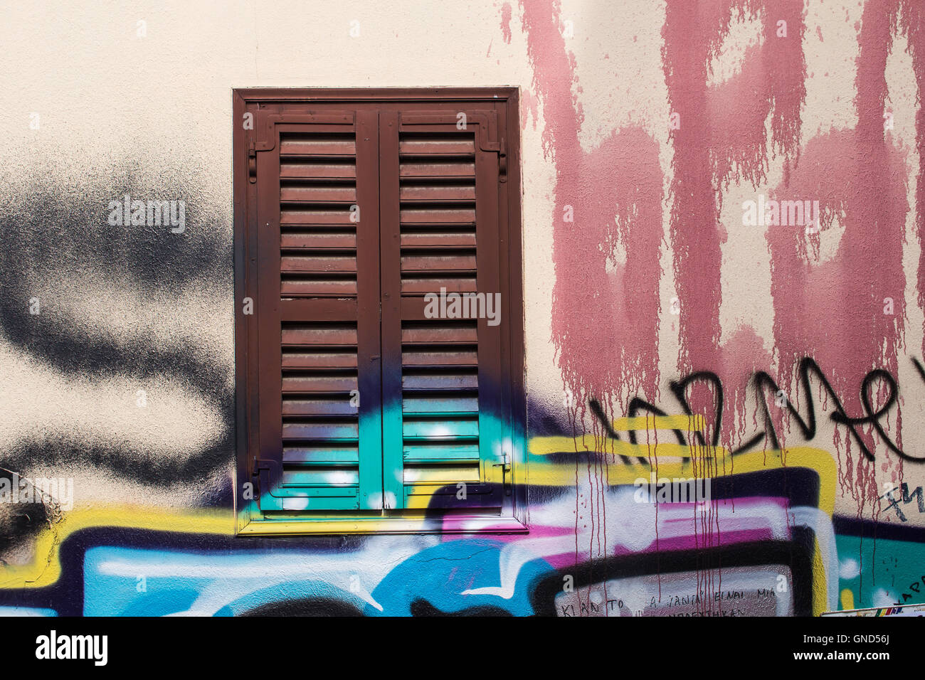 Neutral basic color of the facade of the house. Window covered with brown shutter. Many colorful graffiti tags. Plaka district o Stock Photo