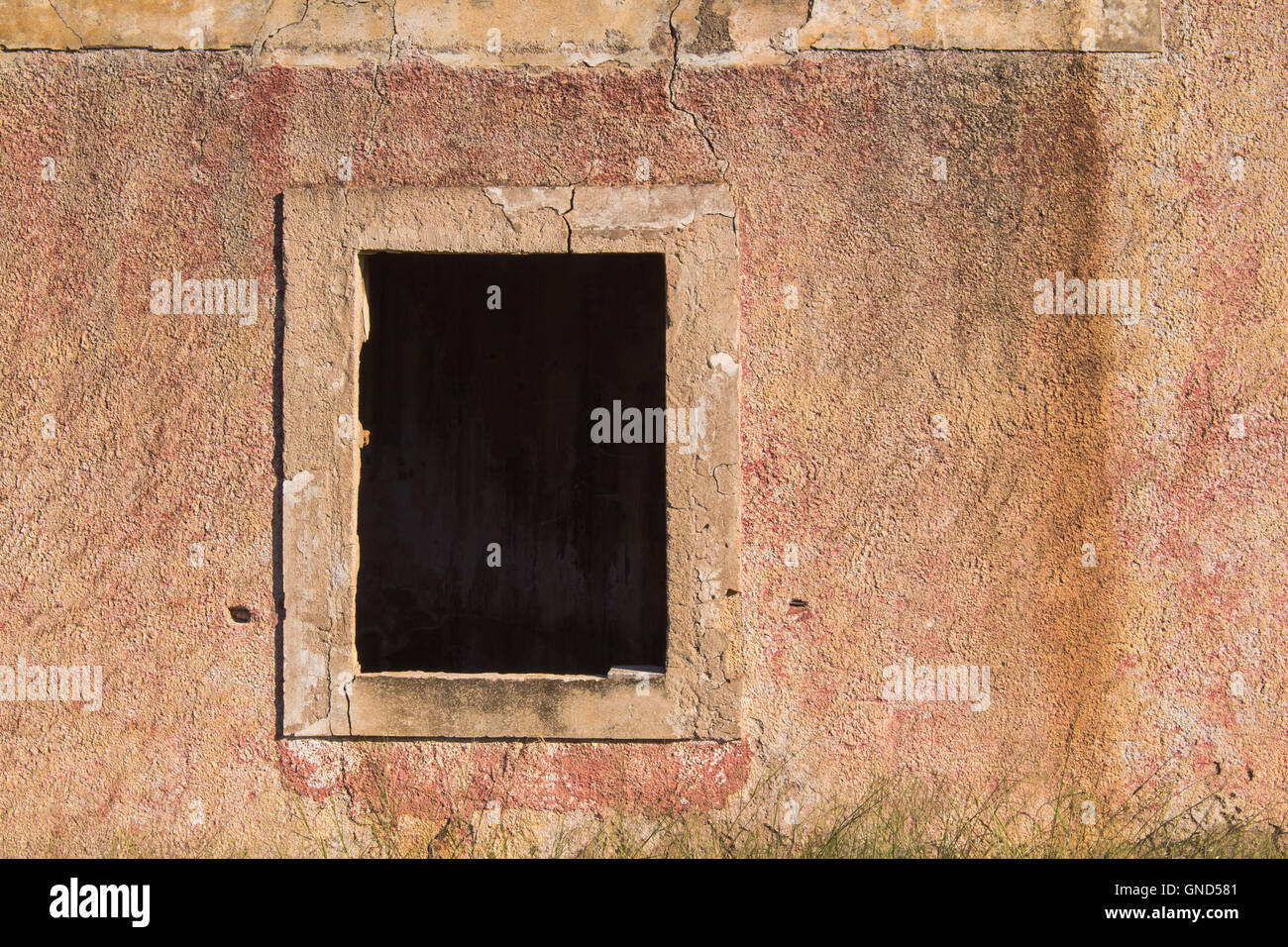 Weathered facade of an abandoned house with a built frame for the window, already without a wooden frame and glass. Stock Photo