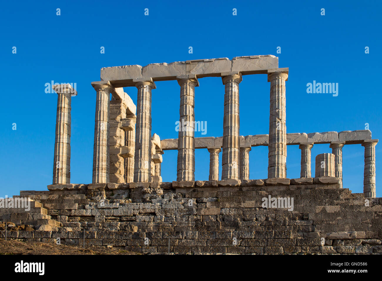 Golden hour light on the columns of  Poseidon temple in Cape Sounion, Greece. Bright blue sky. Stock Photo