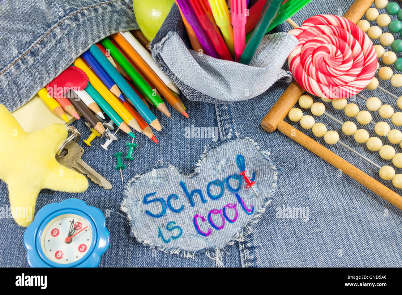 School is cool sign with creative learning objects on blue jeans Stock Photo