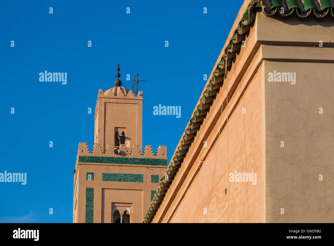 Minaret of one of many mosques in the medina of Marrakesh, enlightened by sun. Traditional architectural details. Bright blue sk Stock Photo