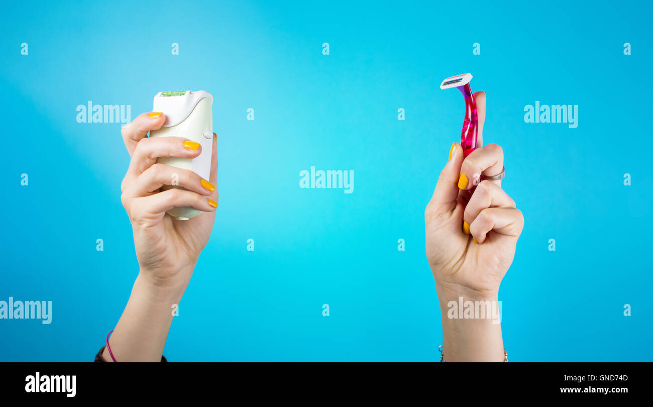 Red shaver and epilator in woman hand. Electric vs manual shave Stock Photo