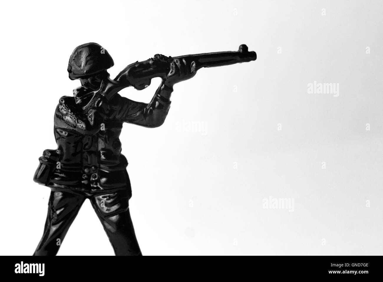 Dramatic toy army soldier aiming rifle in black and white image Stock Photo