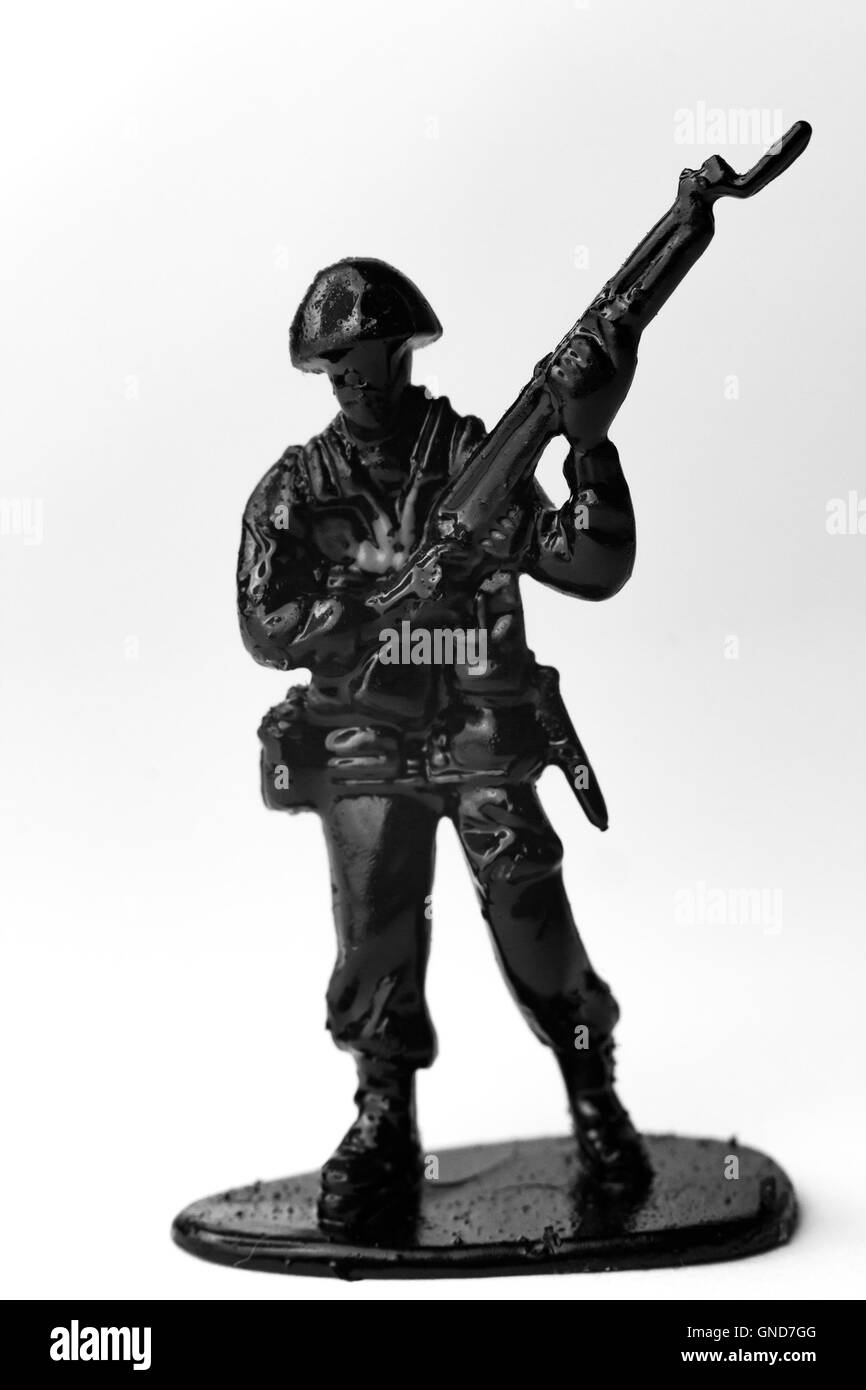Dramatic toy army soldier carrying rifle to battle in black and white image Stock Photo