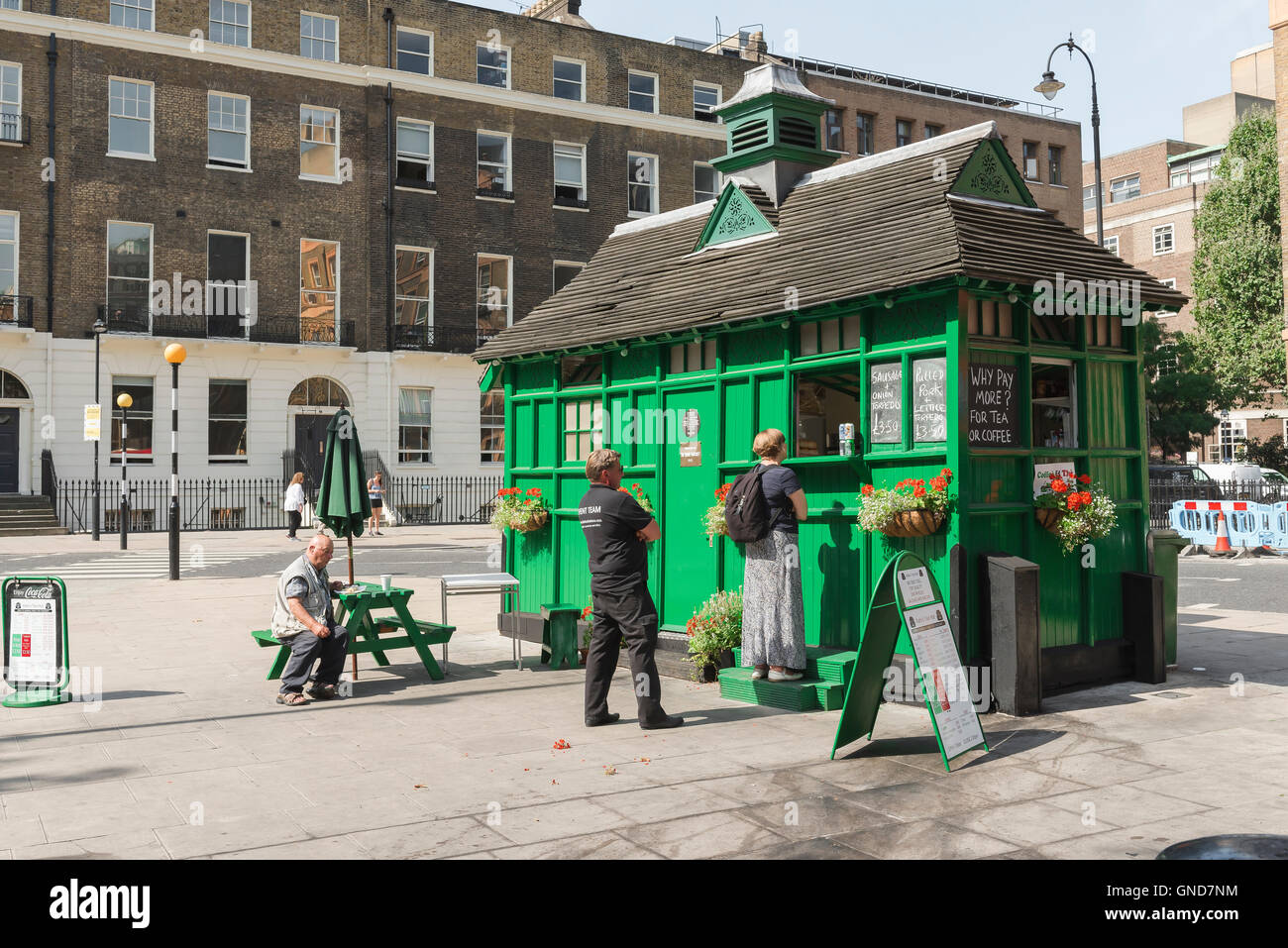 London street food, people buy cooked food from a converted cabmen's shelter in Russell Square, Bloomsbury, London, UK. Stock Photo