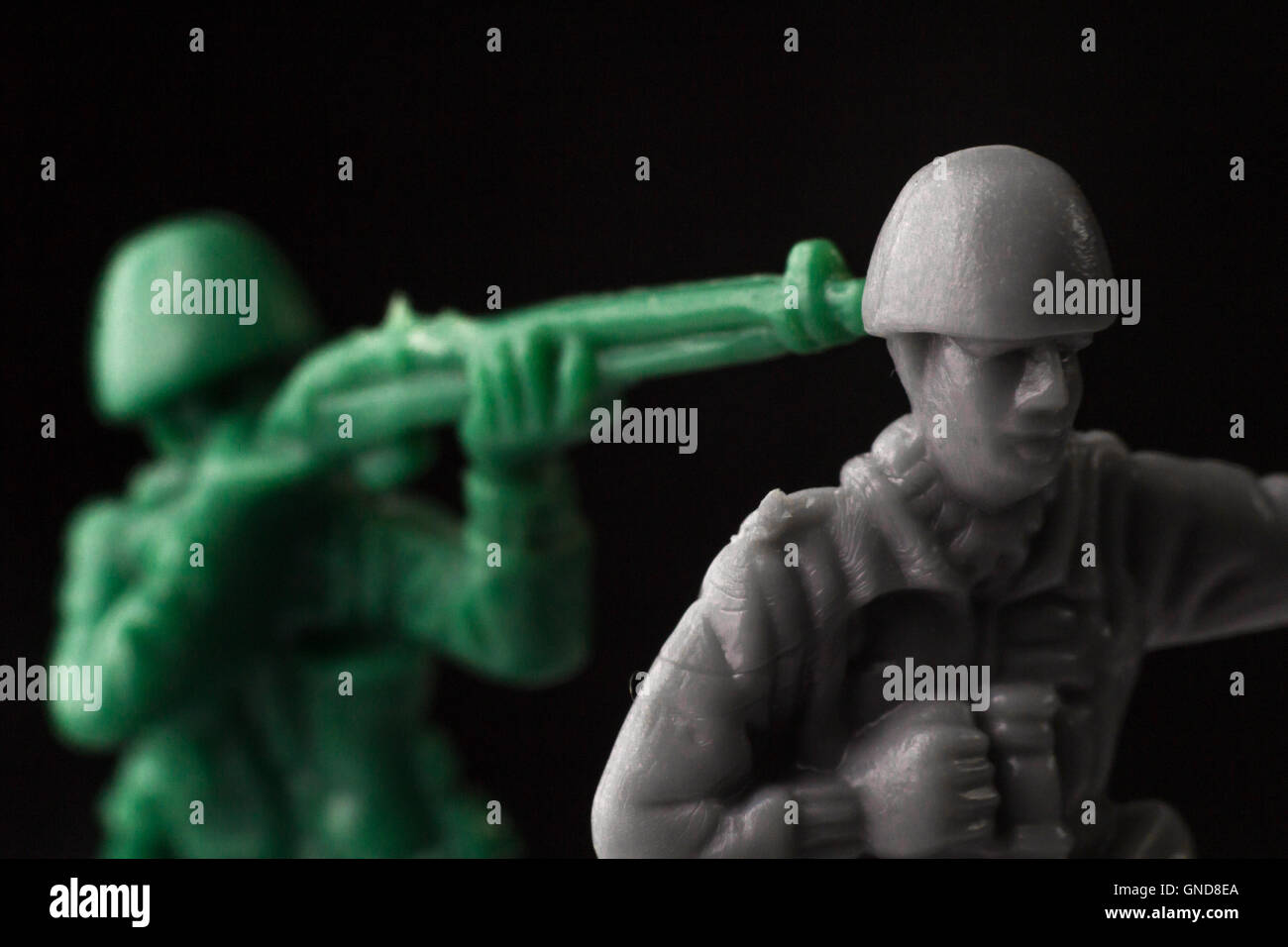 Green toy soldier surprises enemy from behind Stock Photo