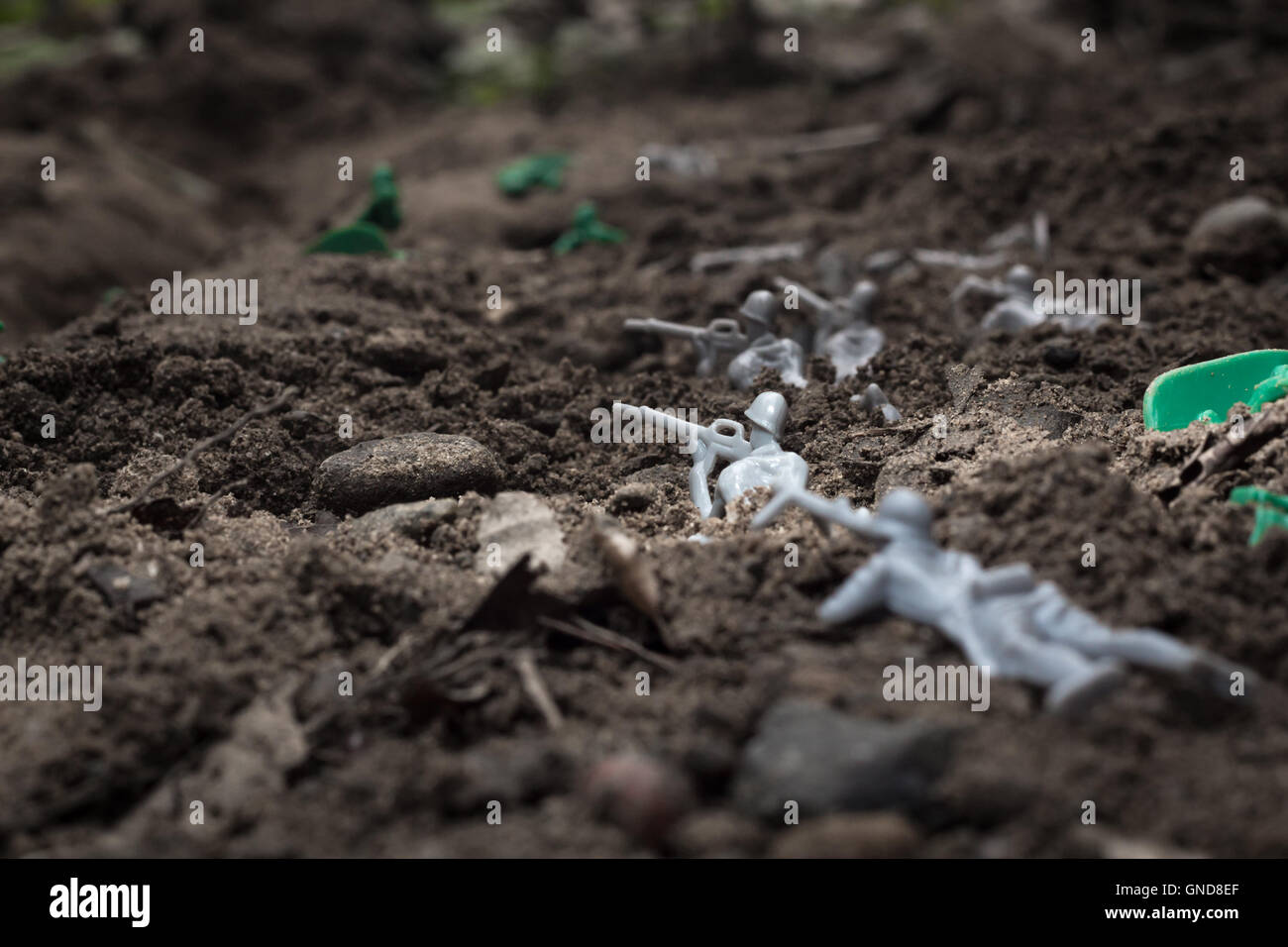 Green toy soldiers in the dirt defending the trenches Stock Photo