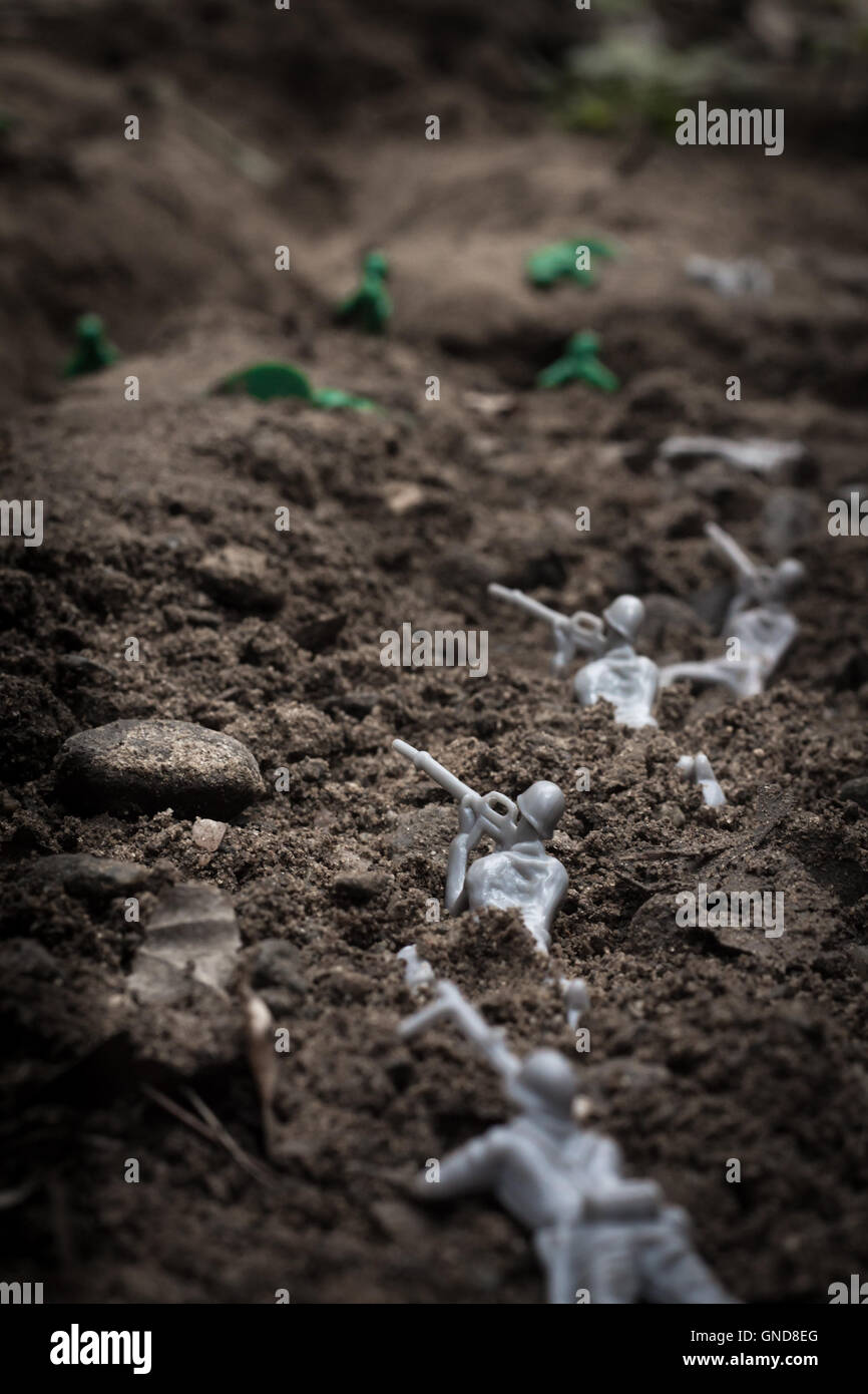 Green toy soldiers in the dirt defending the trenches Stock Photo