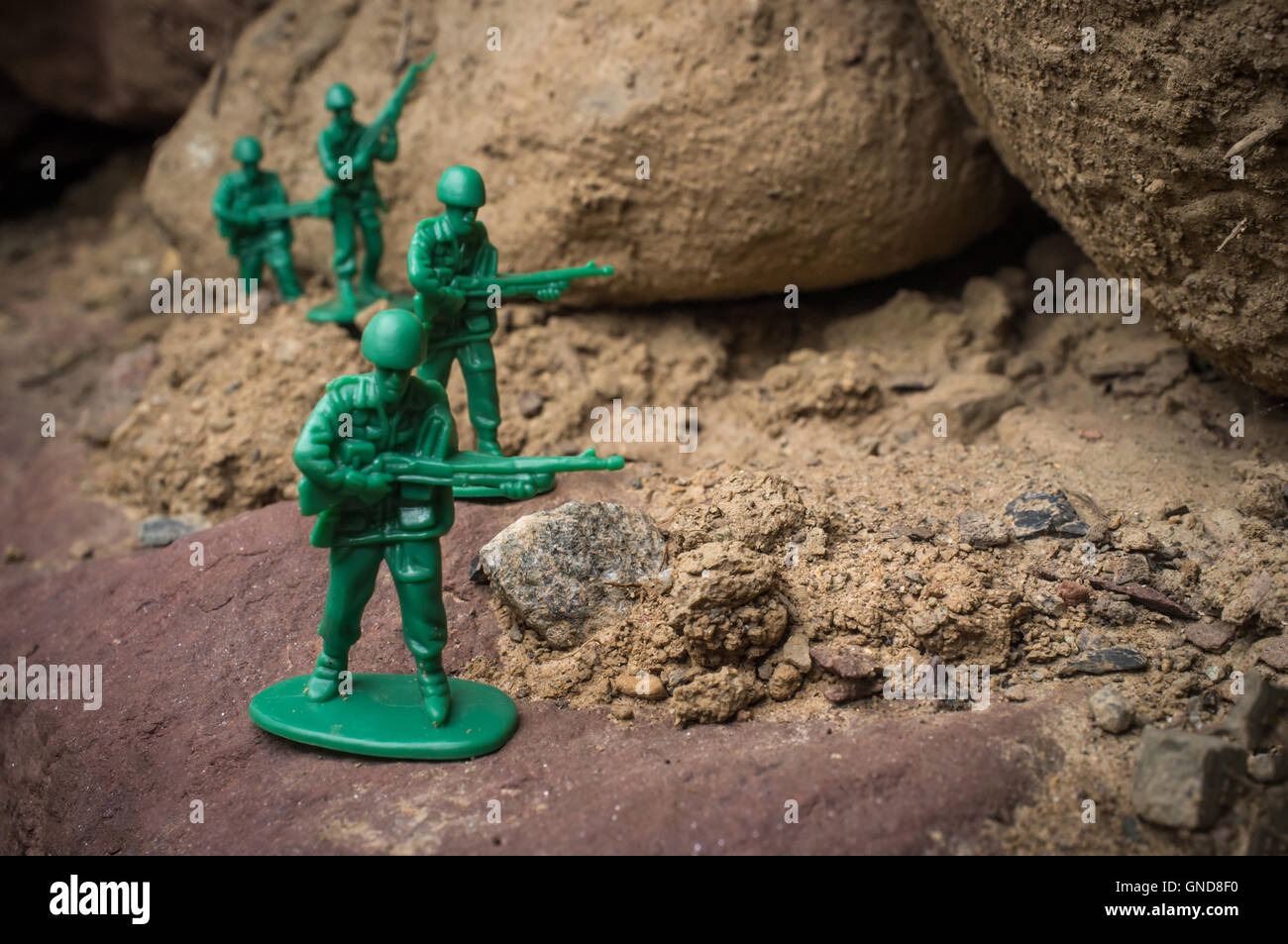 Toy soldiers march along rocky cliffs in natural environment Stock Photo