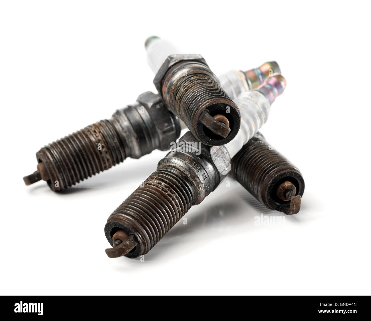 Four used, worn and dirty spark plugs from a car. Stock Photo