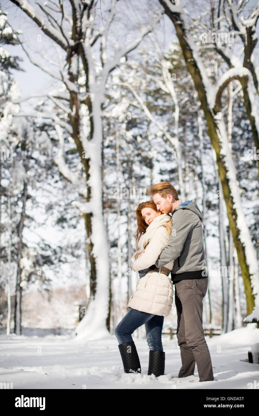 Loving young couple at snow in the winter forest Stock Photo