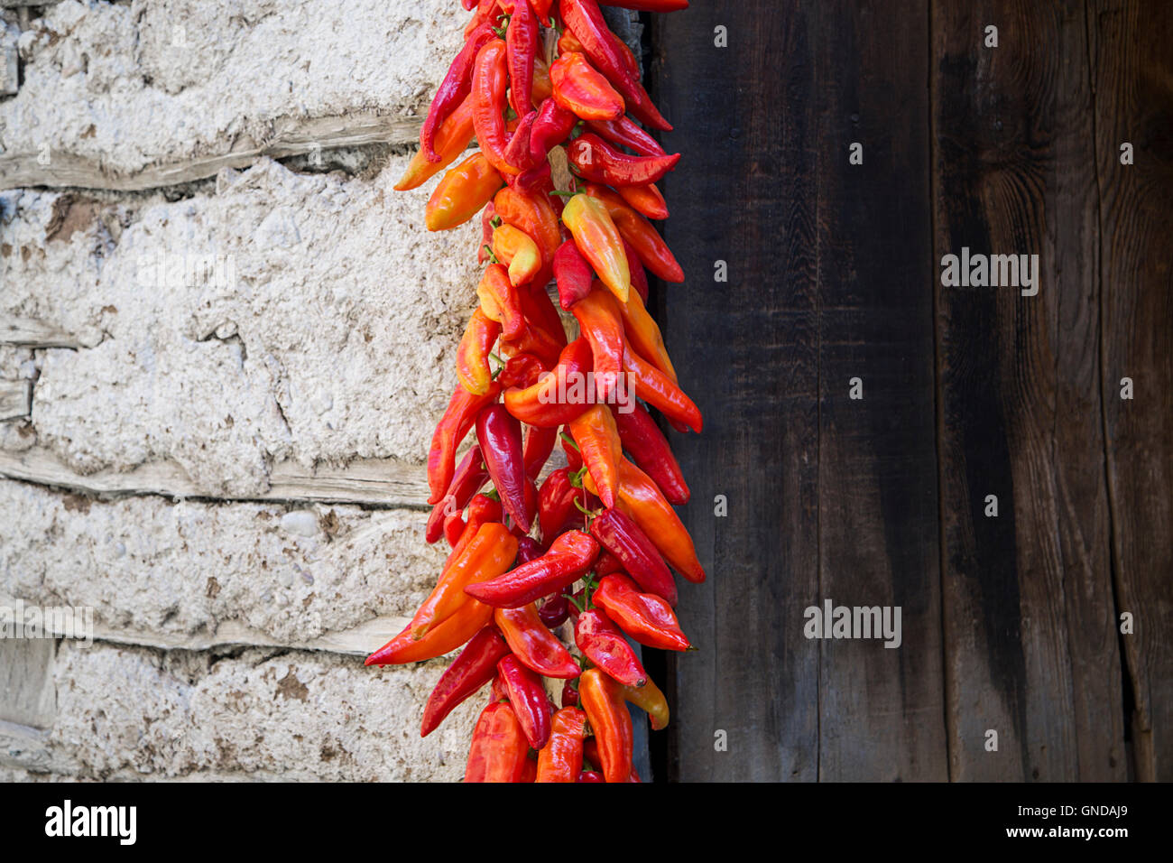 Red Paprika Peppers traditionally hanging To Dry On The Wall Of A House Stock Photo