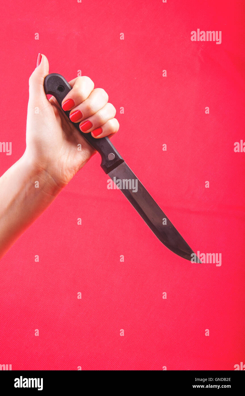 woman's hand holds a knife against red background Stock Photo