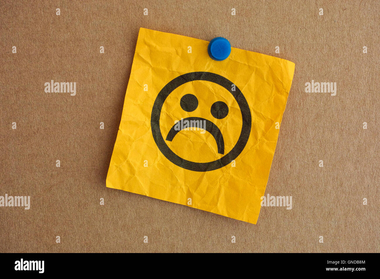 Paper note with sad face. Closeup. Stock Photo