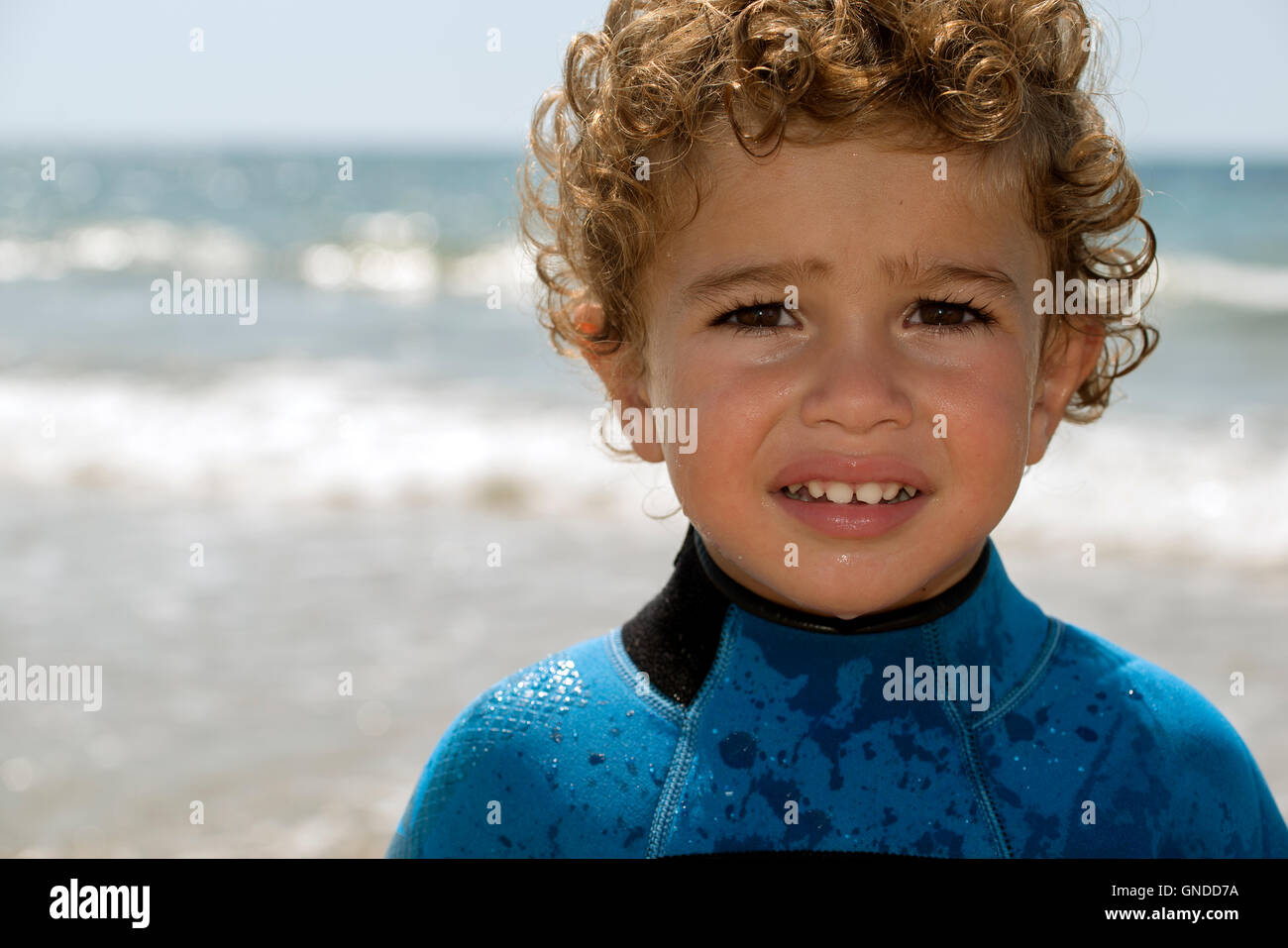 portrait of young boy by a sand beach in diving suit Stock Photo