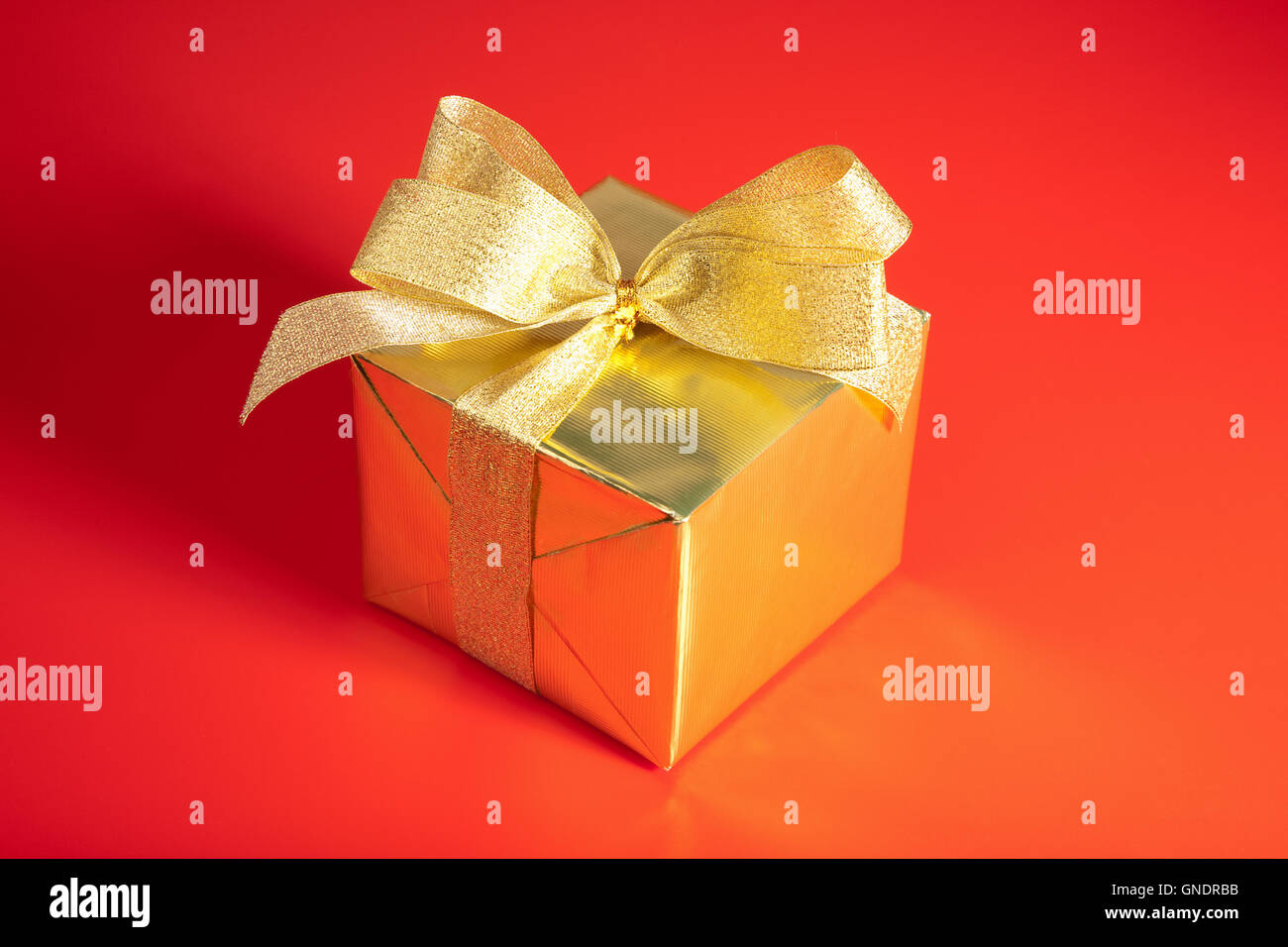 golden gift box with bow over red background Stock Photo - Alamy