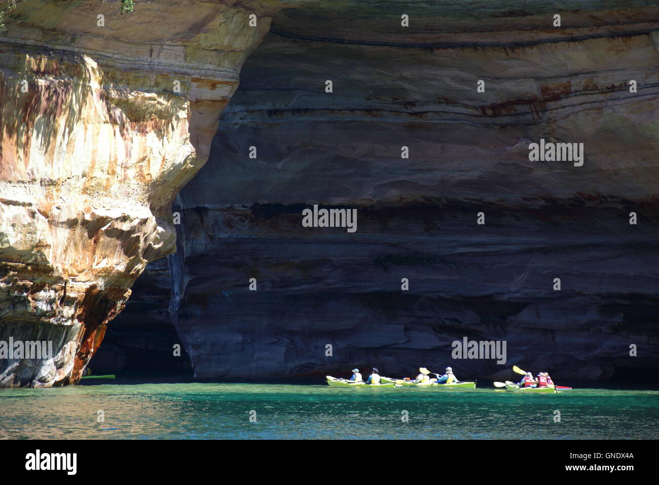 Group of kayakers paddling through Lover's Leap arc at Pictured Rocks National Park, MI, USA Stock Photo