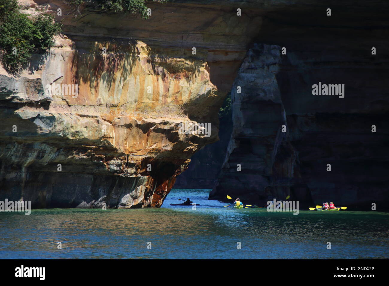 Group of kayakers paddling through Lover's Leap arc at Pictured Rocks National Park, MI, USA Stock Photo