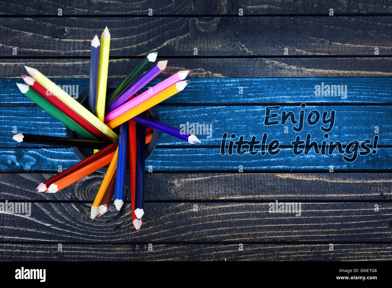 Enjoy little things text painted and group of pencils on wooden table Stock Photo