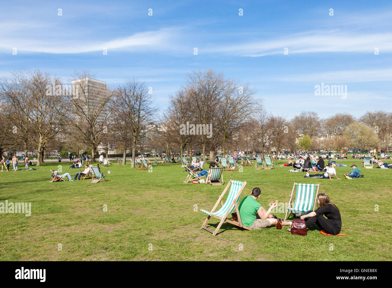 People sitting in the April sunshine at Hyde Park, London, England, UK Stock Photo