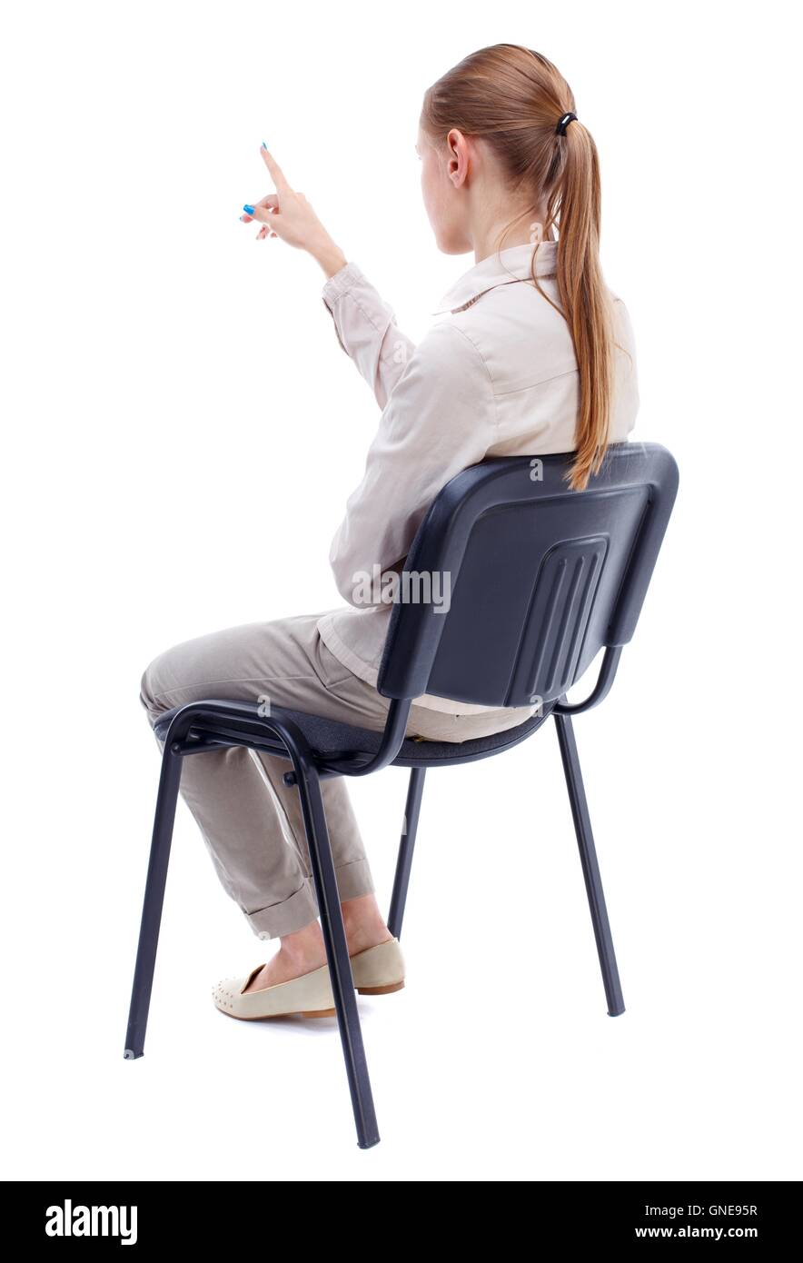 back view of young beautiful  woman sitting on chair and pointin Stock Photo