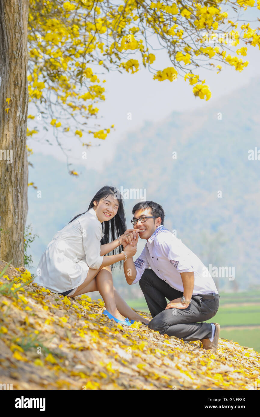 portrait of asia happy young couple sitting on yellow tree Stock Photo